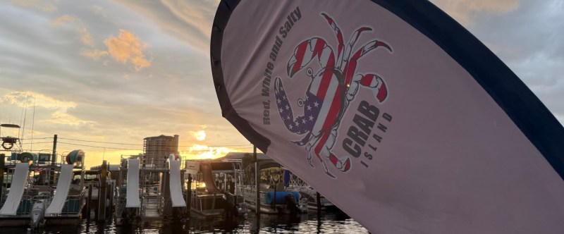 Sunset at marina with flag and boat slips visible.